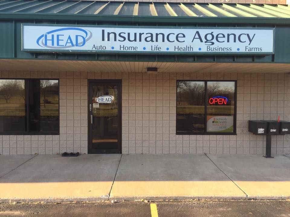 A man and a woman are sitting at a table looking at a laptop.