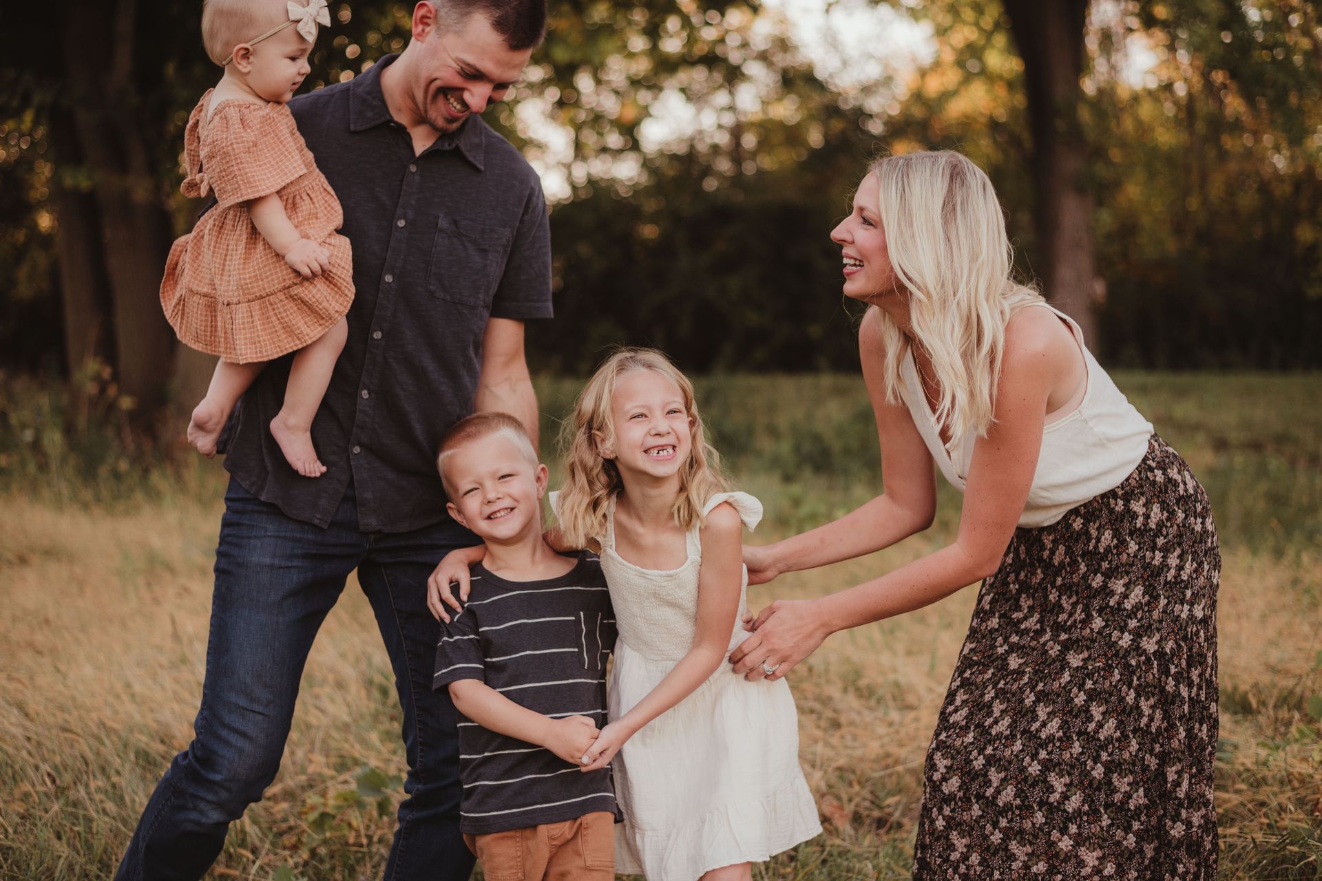 A family is sitting at a table looking at a laptop computer.