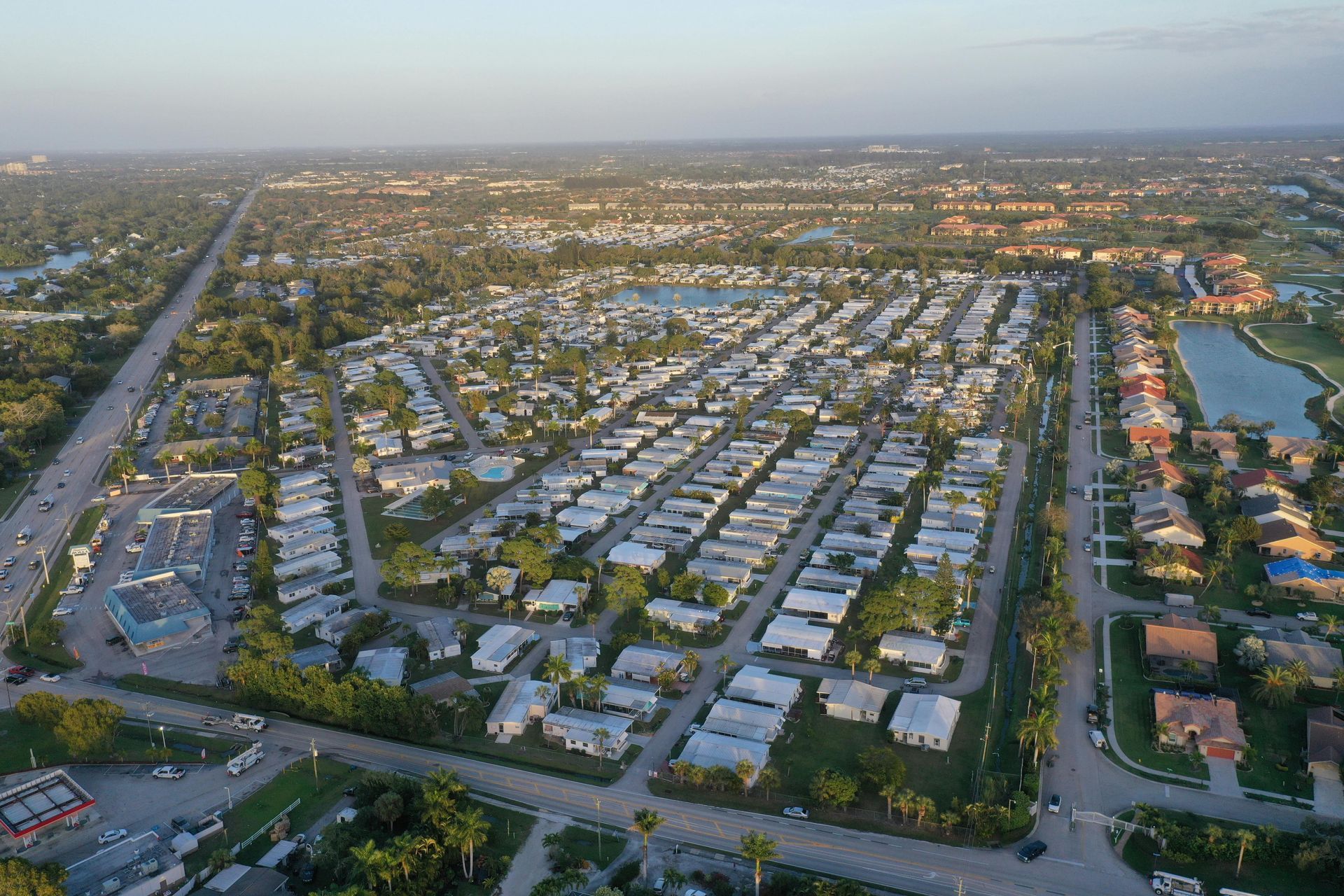 Aerial view of a dense residential area with rows of houses and a large pond, possibly Florida.