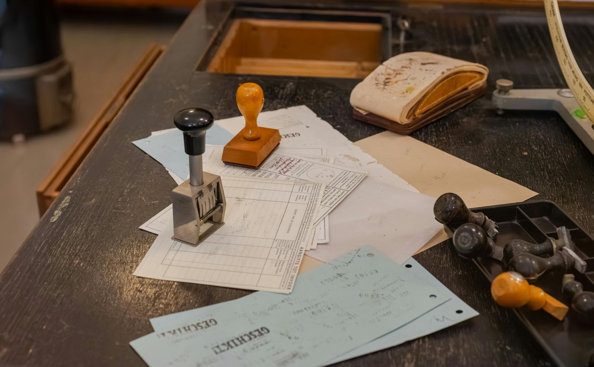 Close-up of old office desk with stamps, papers, and an eraser.