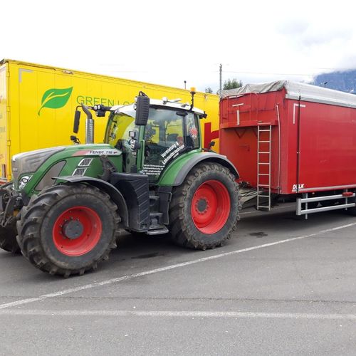 Ein grüner Traktor steht neben einem roten Anhänger