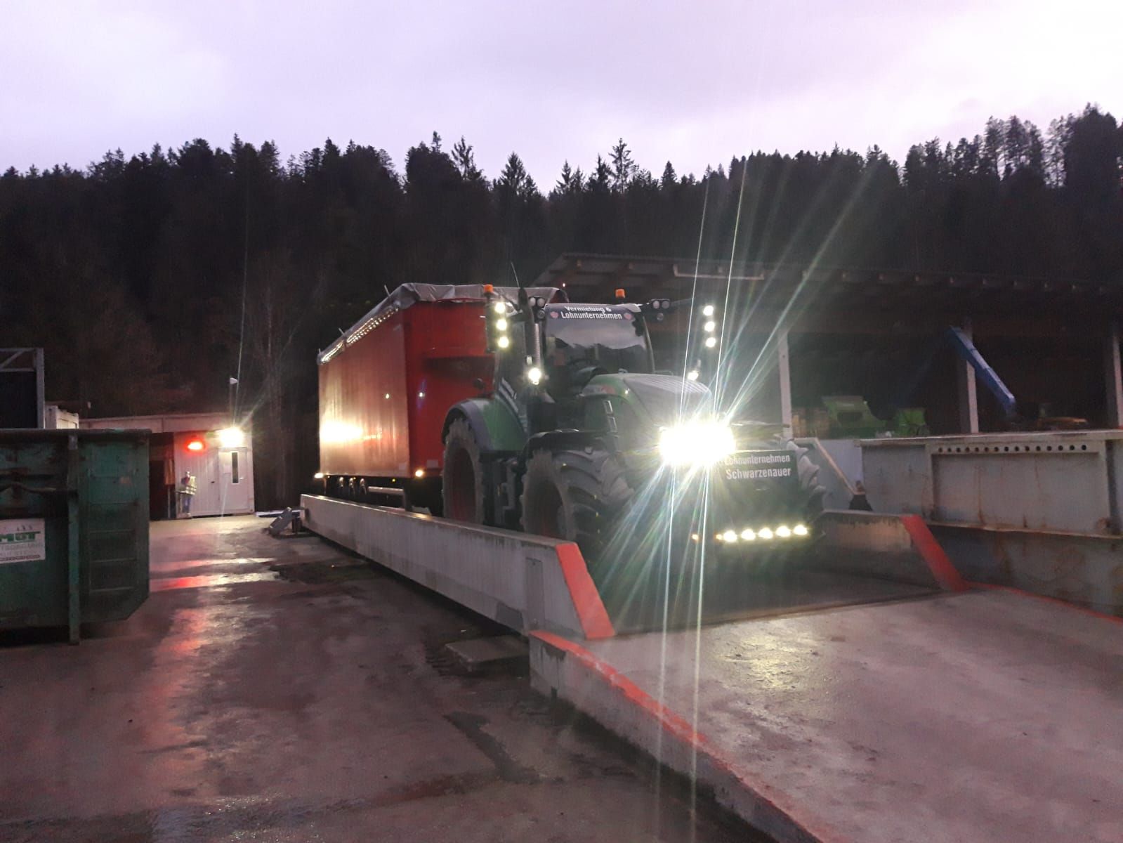 Ein Traktor fährt nachts eine Waage hinunter.