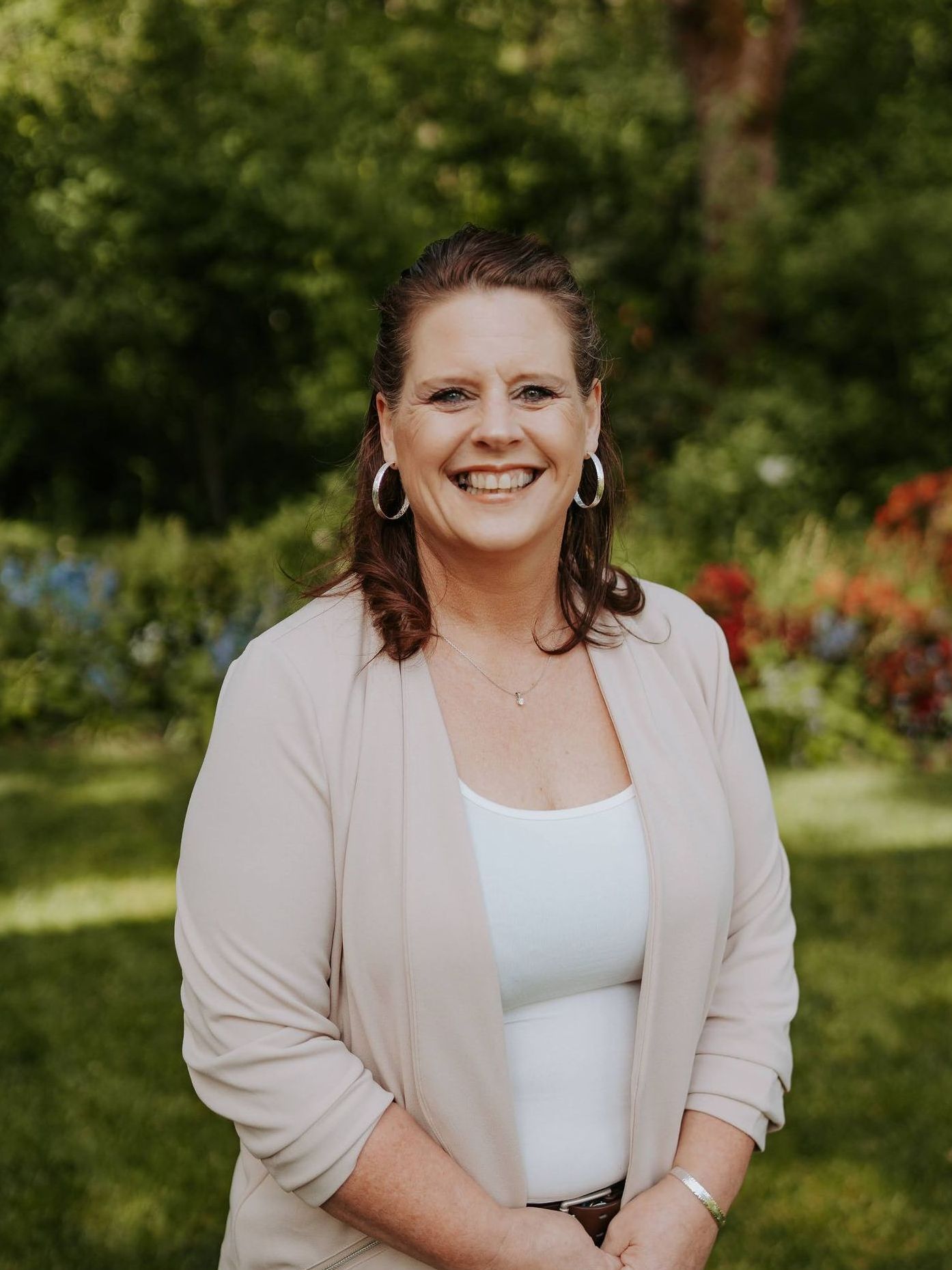 A woman is smiling for the camera while standing in a garden.