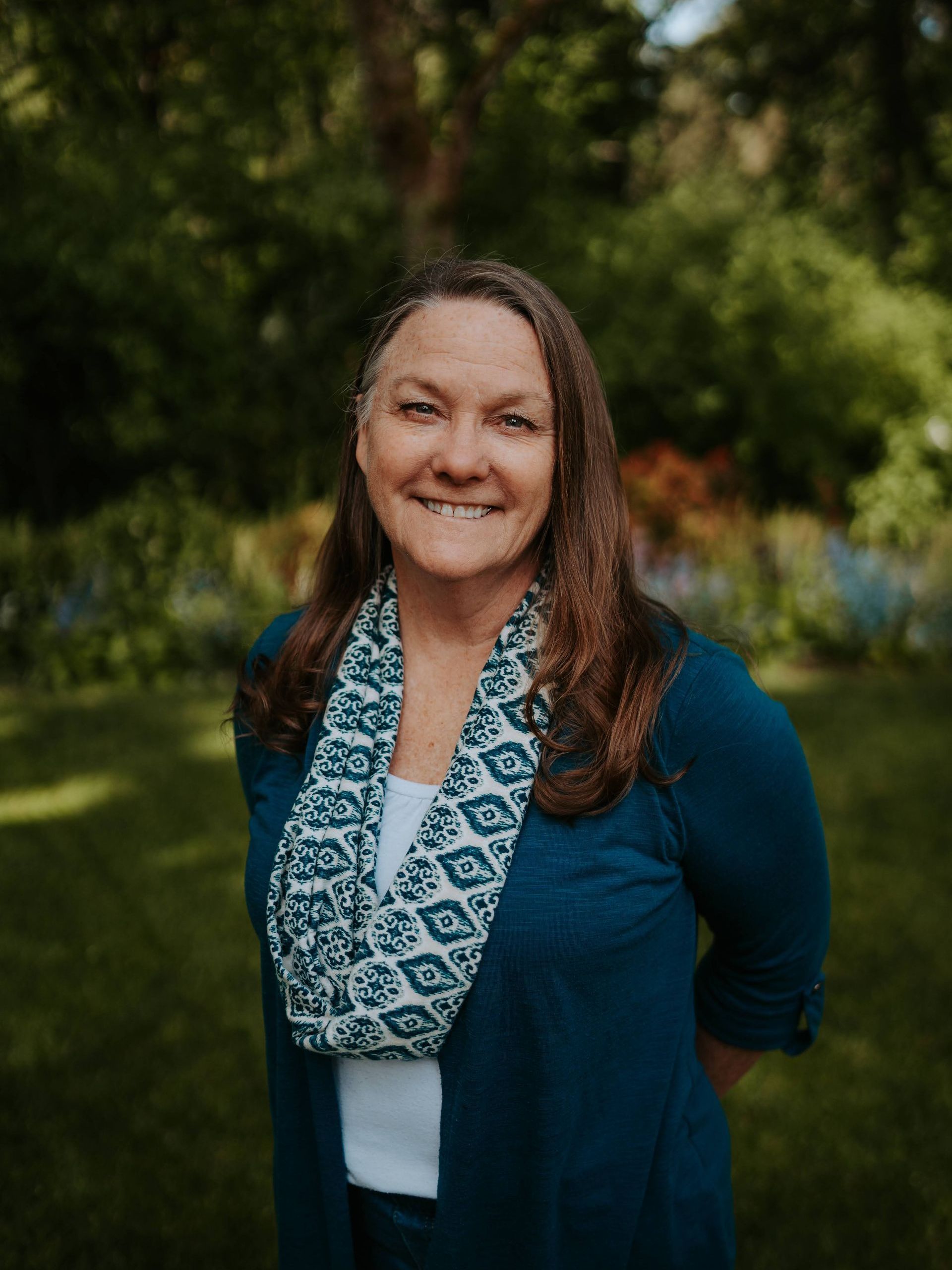 A woman in a blue jacket and scarf is smiling for the camera.