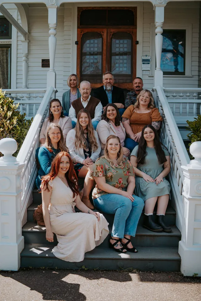A man in a gray shirt is standing in a field with mountains in the background.