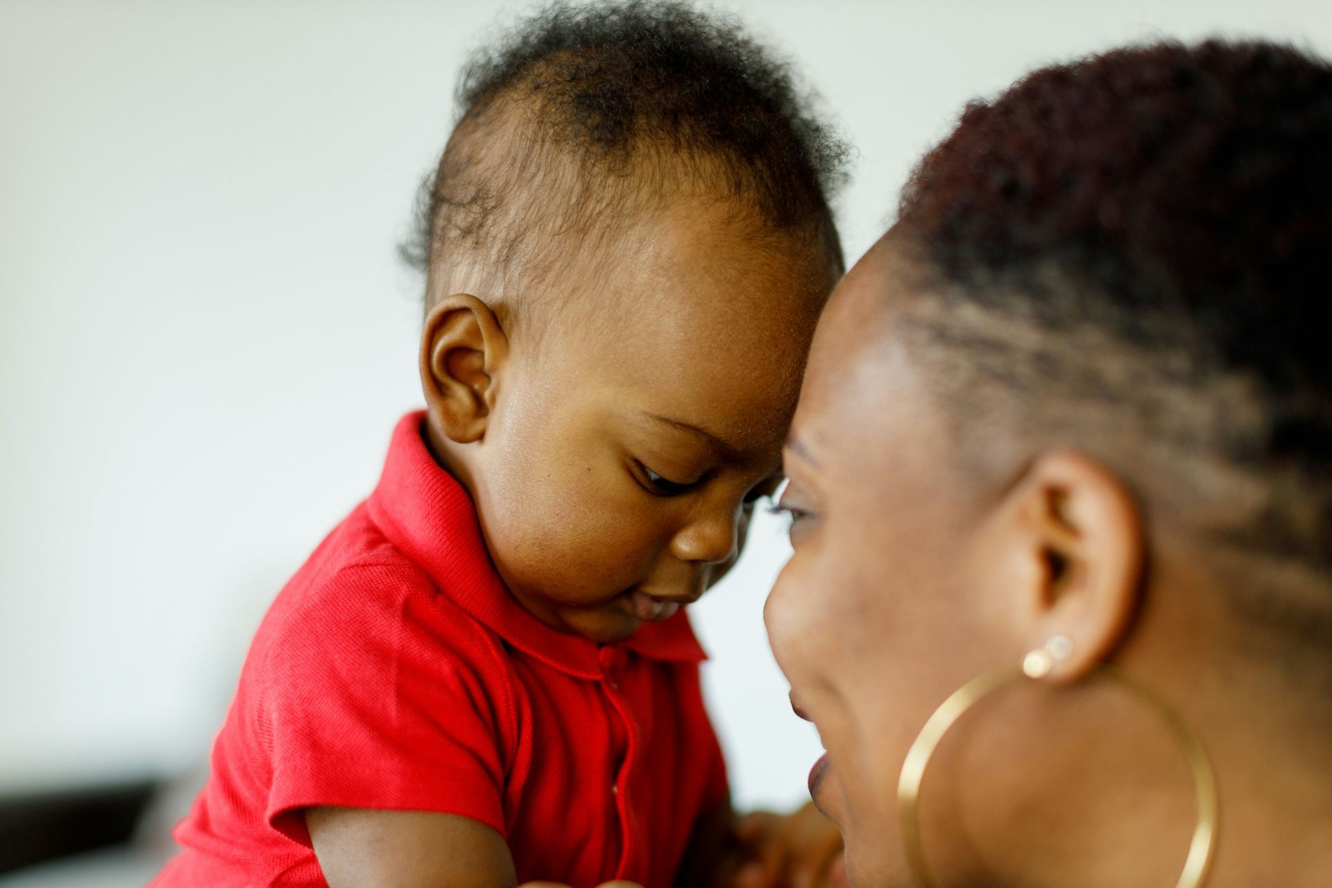 A woman is holding a baby in her arms and the baby is looking at the camera.