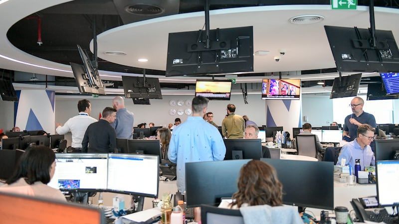 A group of people are sitting at desks in an office.