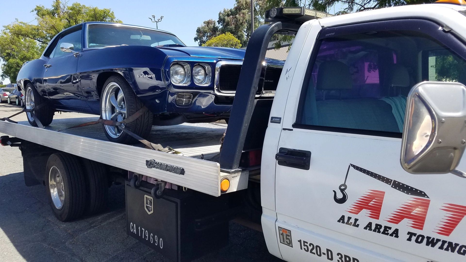 A man is towing a car on a tow truck.