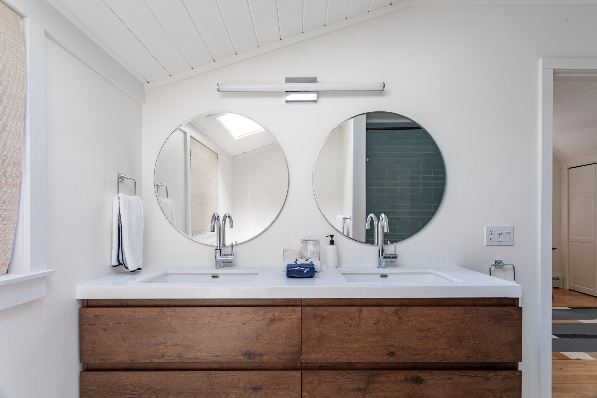 A bathroom vanity with two round mirrors above a double sink and wooden cabinet. A bathroom vanity with two round mirrors above a double sink and wooden cabinet.
