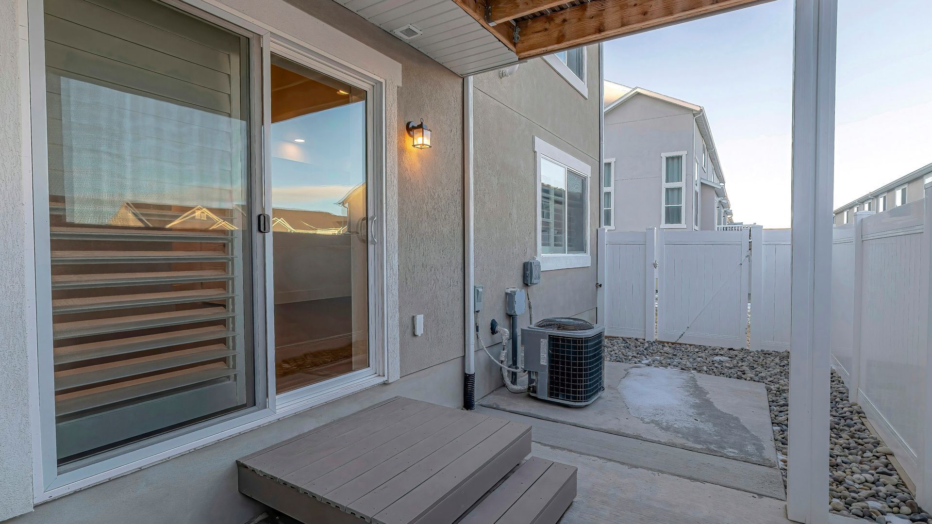 Sliding glass doors open to a small backyard patio beside an exterior air conditioning unit
