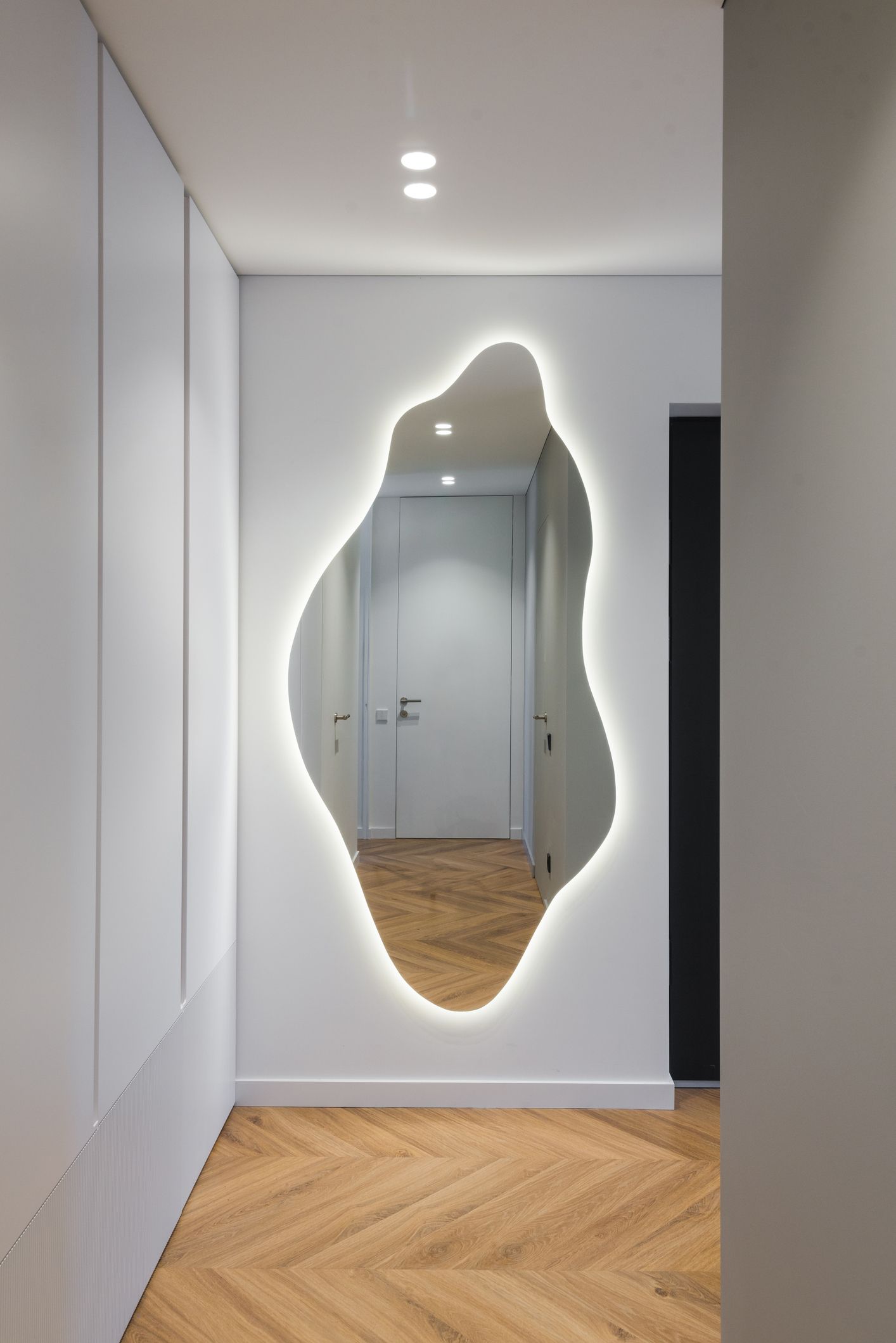 Stylish backlit mirror in apartment corridor by closet.