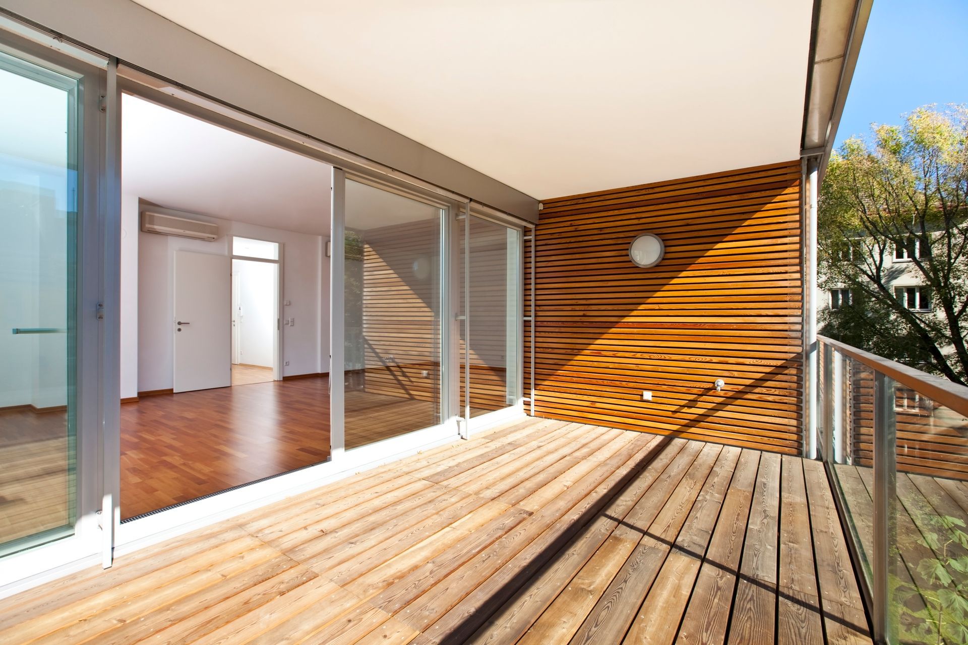 Contemporary balcony bathed in sunlight, highlighting elegant architecture and mirror details.