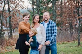 A family is posing for a picture in the woods.