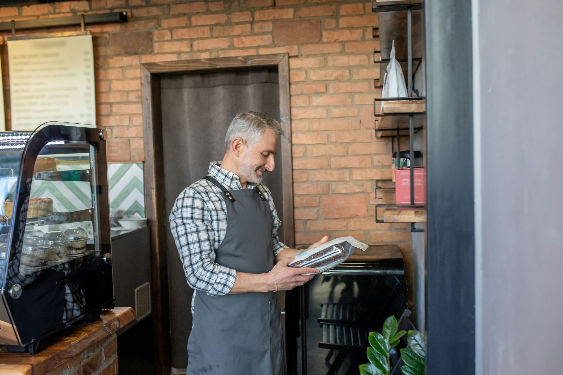 Poolside outdoor bar with TV, seating, and lounge chair under a pergola roof, with trees in the background.