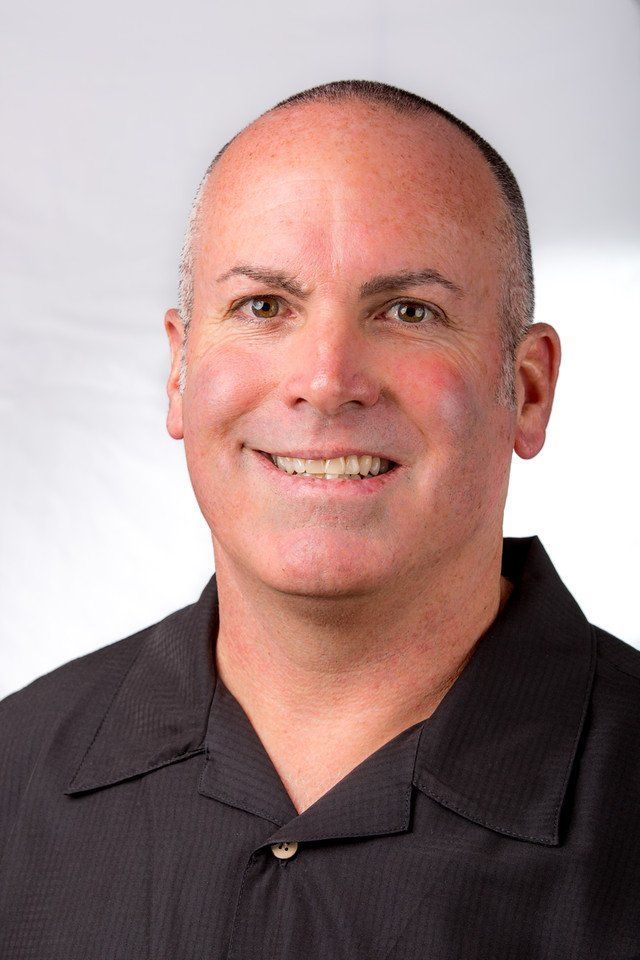 Two people doing yoga outside. One in pink, one in white, arms outstretched, smiling.