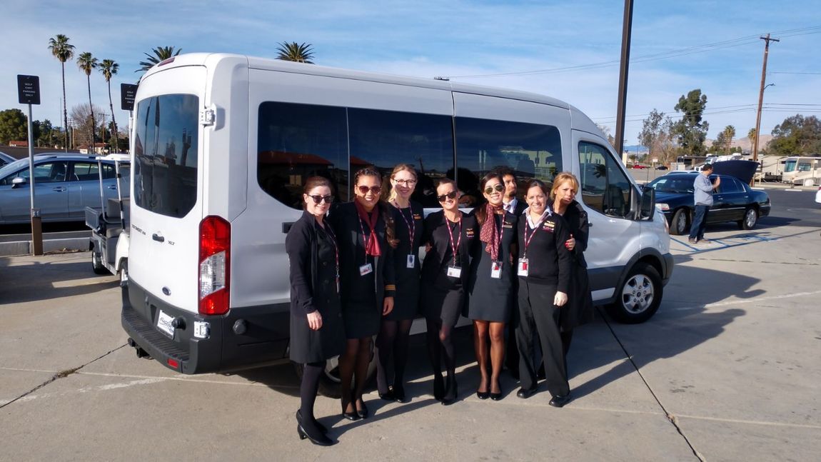 A group of people are posing for a picture in front of a white van.