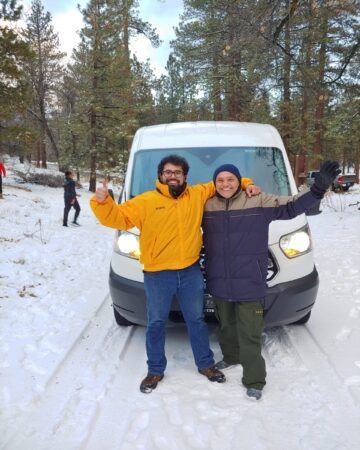 Two men standing in front of a van in the snow