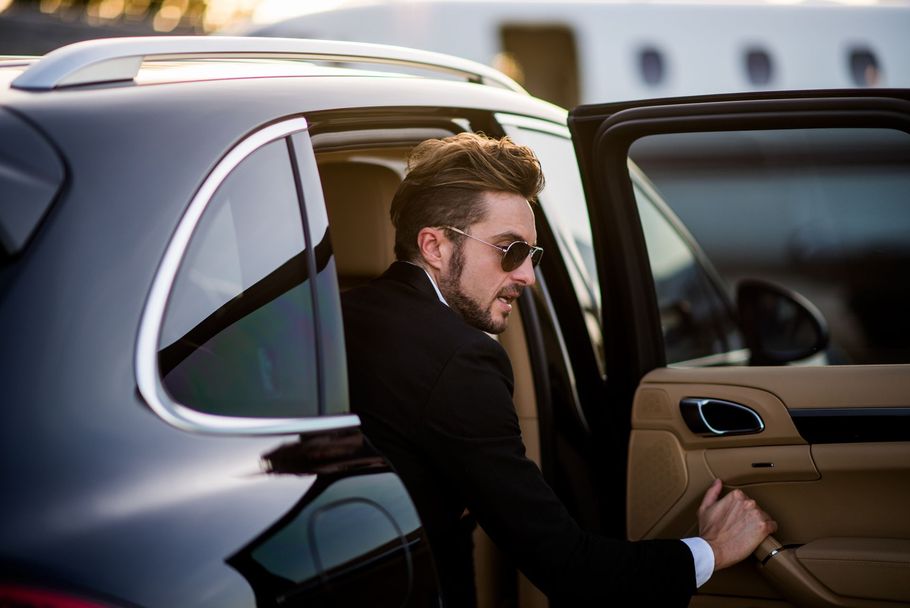 A man in a suit and sunglasses is getting out of a car.