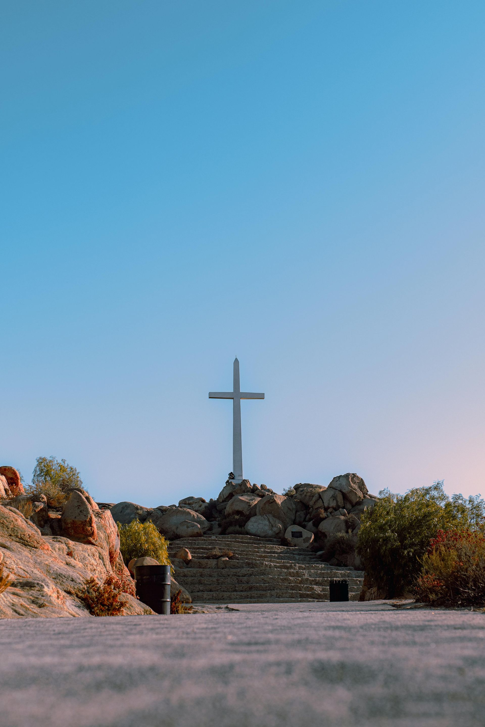 A large cross is sitting on top of a rocky hill.