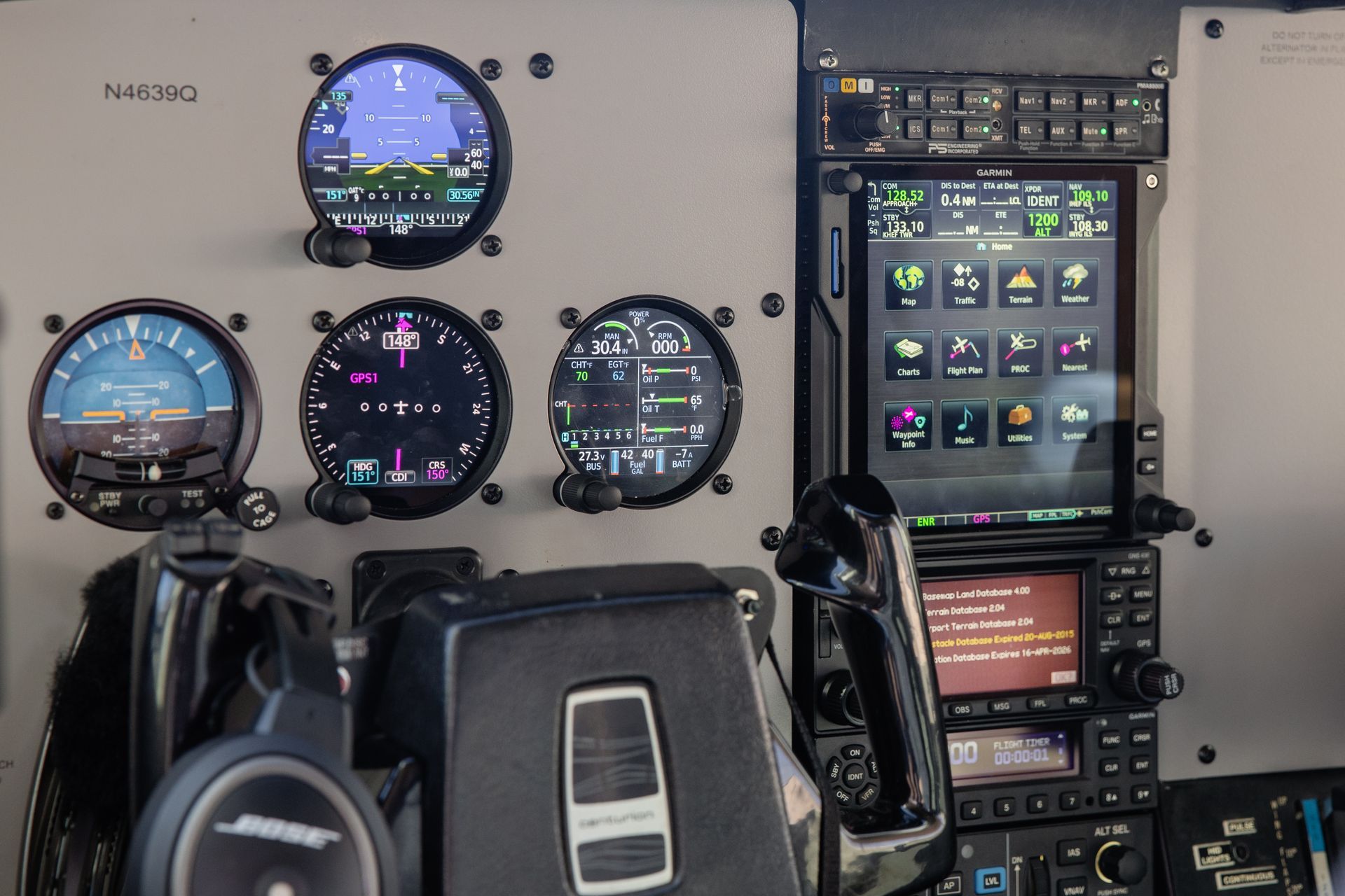 Cockpit panel with flight instruments, GPS display, and headset in an aircraft interior