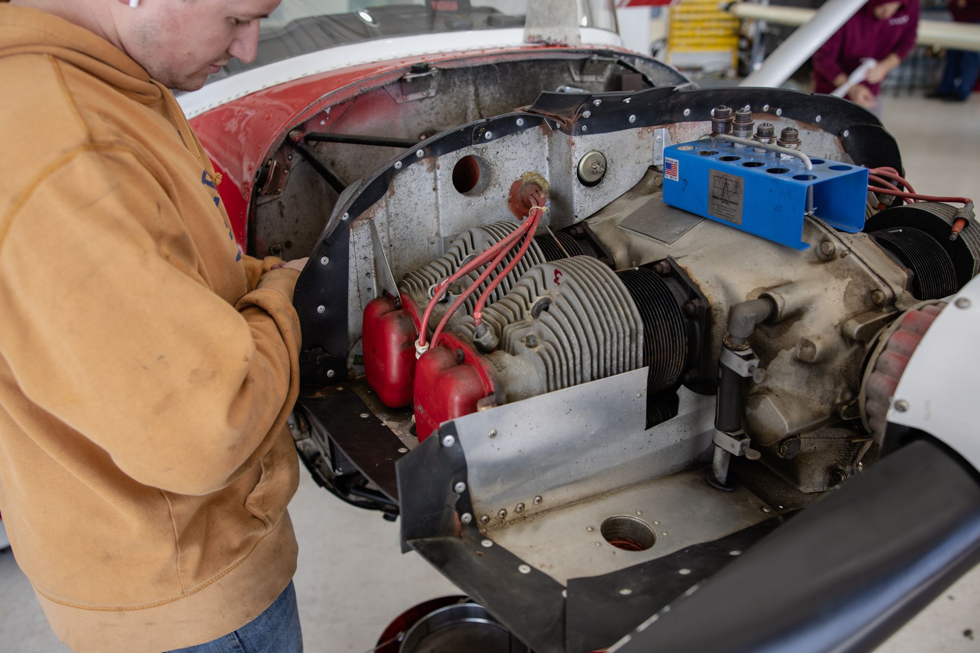Person inspecting an exposed engine in a small aircraft