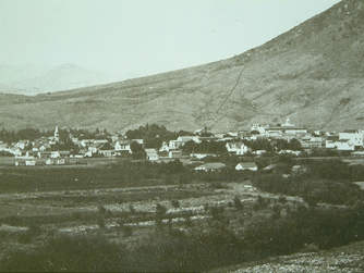 A black and white photo of a small town with a mountain in the background