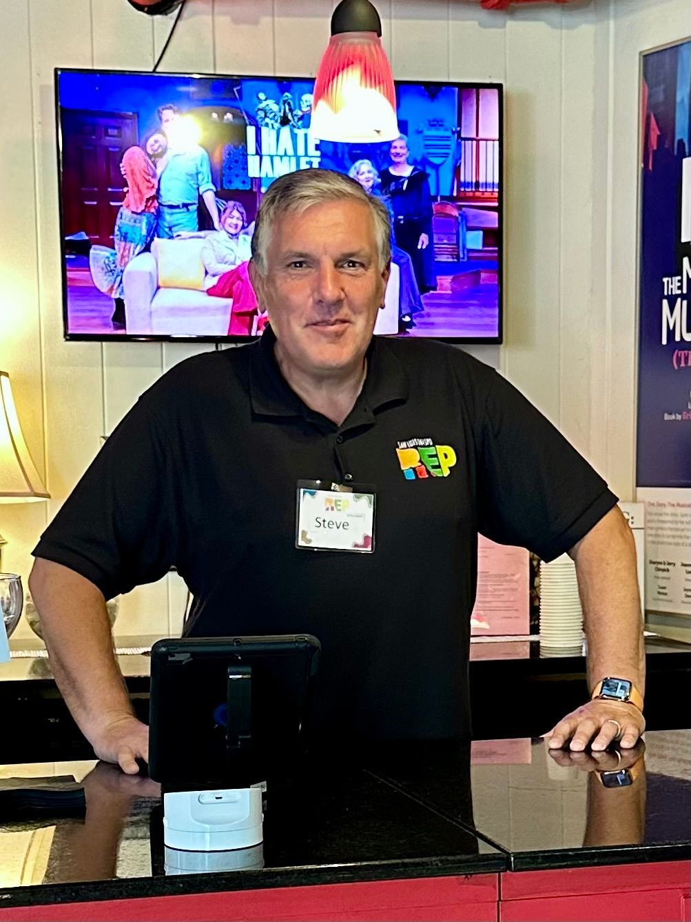 A man with a mustache is wearing a suit and bow tie