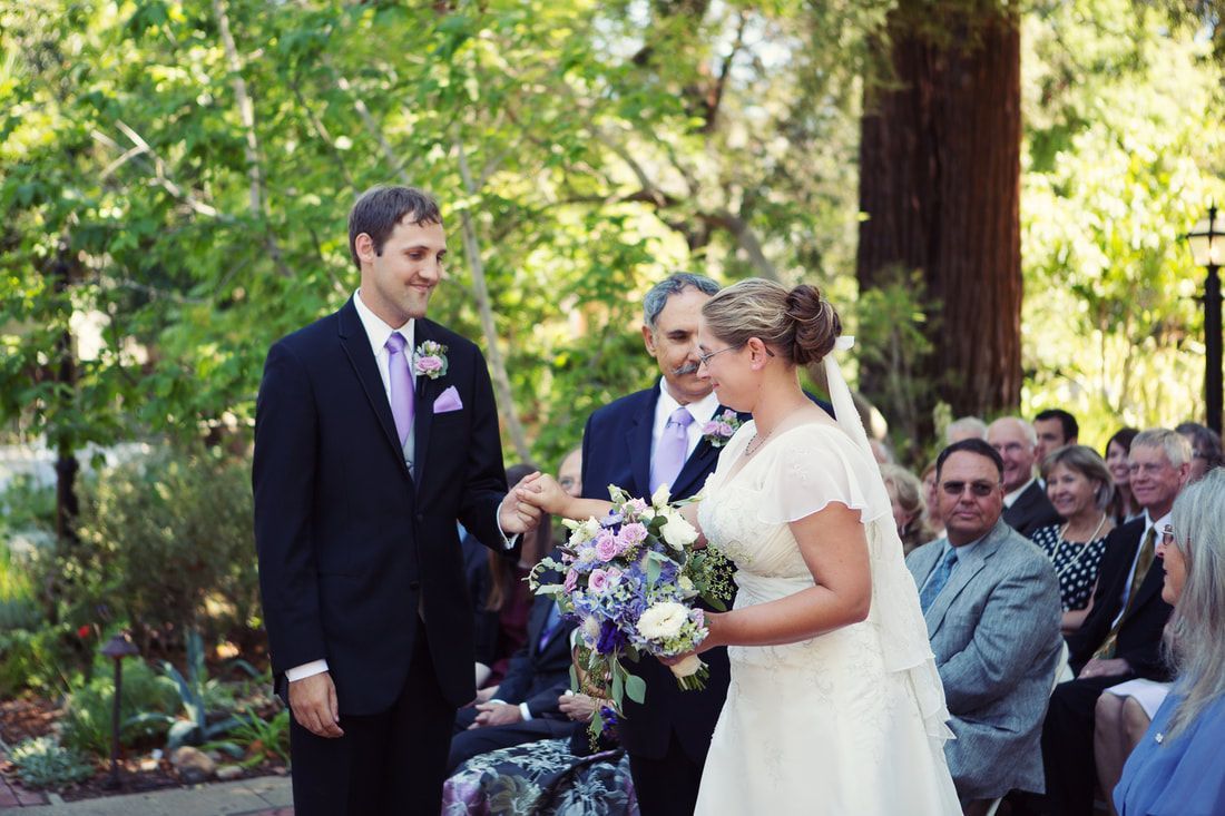 A bride and groom are shaking hands at their wedding ceremony.