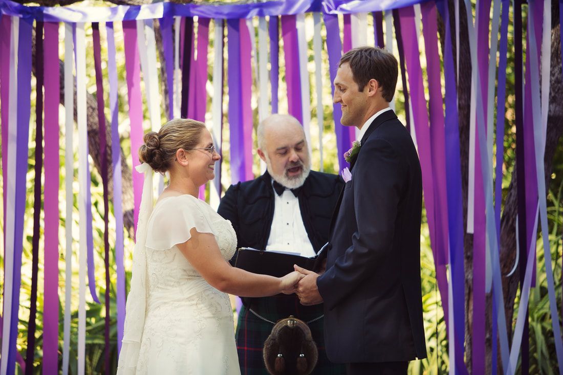 A bride and groom are holding hands during their wedding ceremony.
