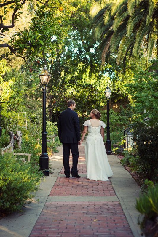 A bride and groom are walking down a brick walkway holding hands.