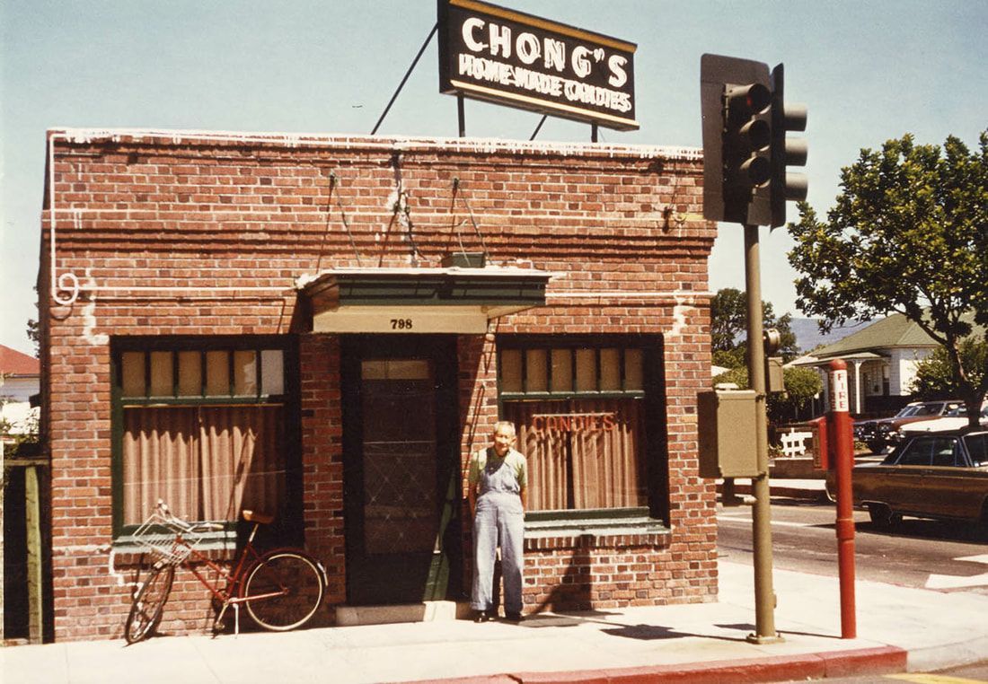 A man stands in front of a building that says chong 's