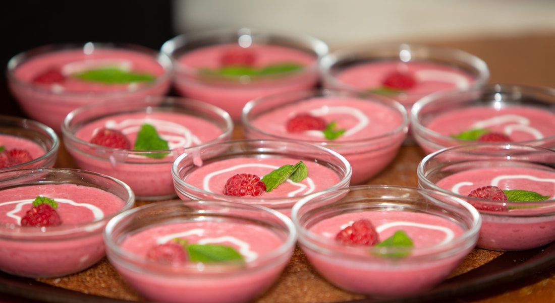 A tray of pink desserts with raspberries on top.