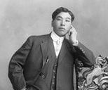 A black and white photo of a man in a suit talking on a cell phone.