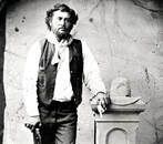 A black and white photo of a man standing next to a cowboy hat.