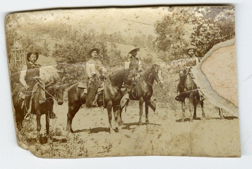 A group of people riding horses in a field