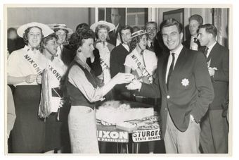 A group of people standing around a table with a sign that says nixon