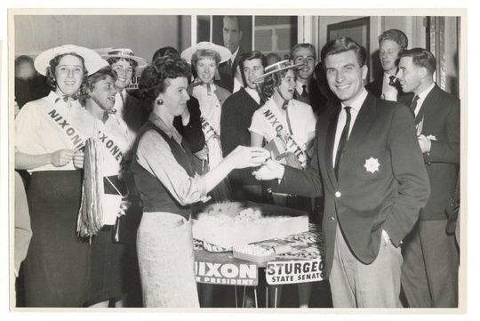 A group of people standing around a table with a sign that says nixon