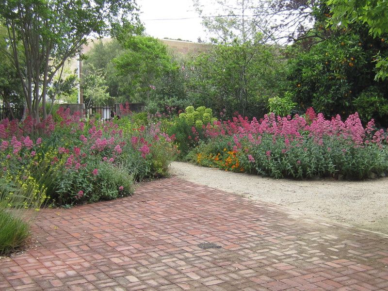A brick driveway surrounded by flowers and trees