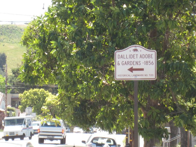 A sign on the side of the road points to dalliet adobe and gardens