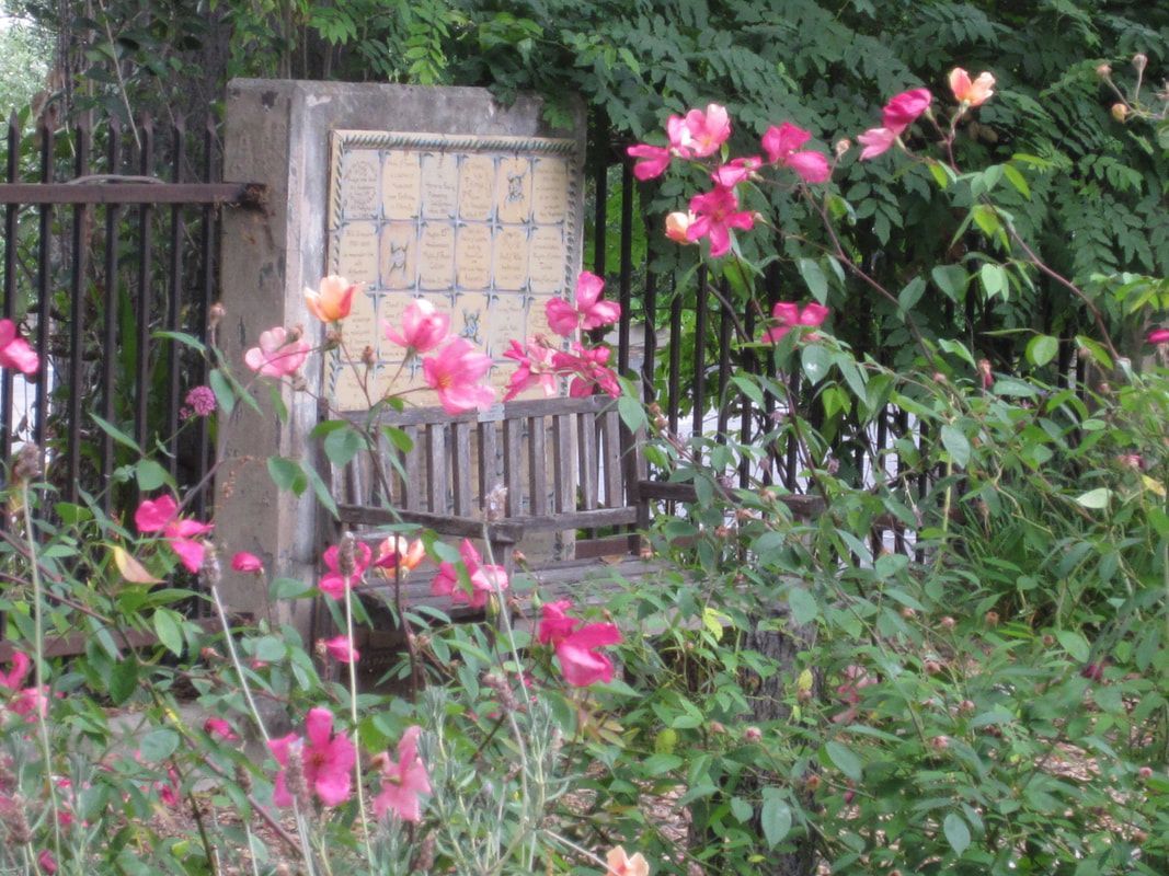 A clock is surrounded by pink flowers and a fence.