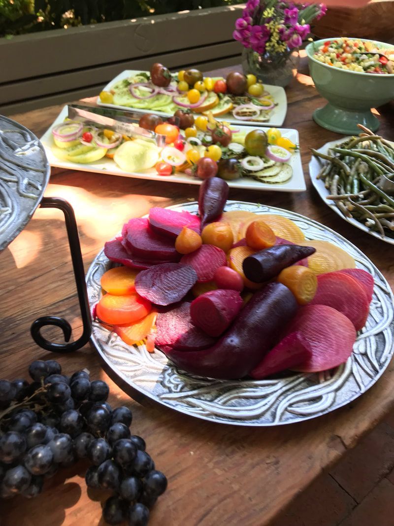 A wooden table topped with plates of fruit and vegetables.