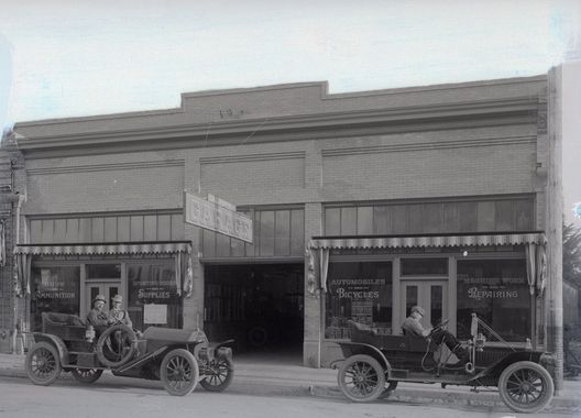 Two old cars are parked in front of a building.