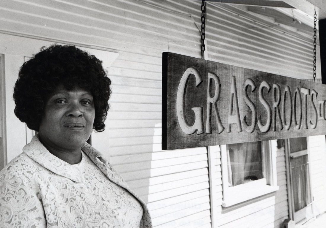 A woman is standing in front of a sign that says grassroots