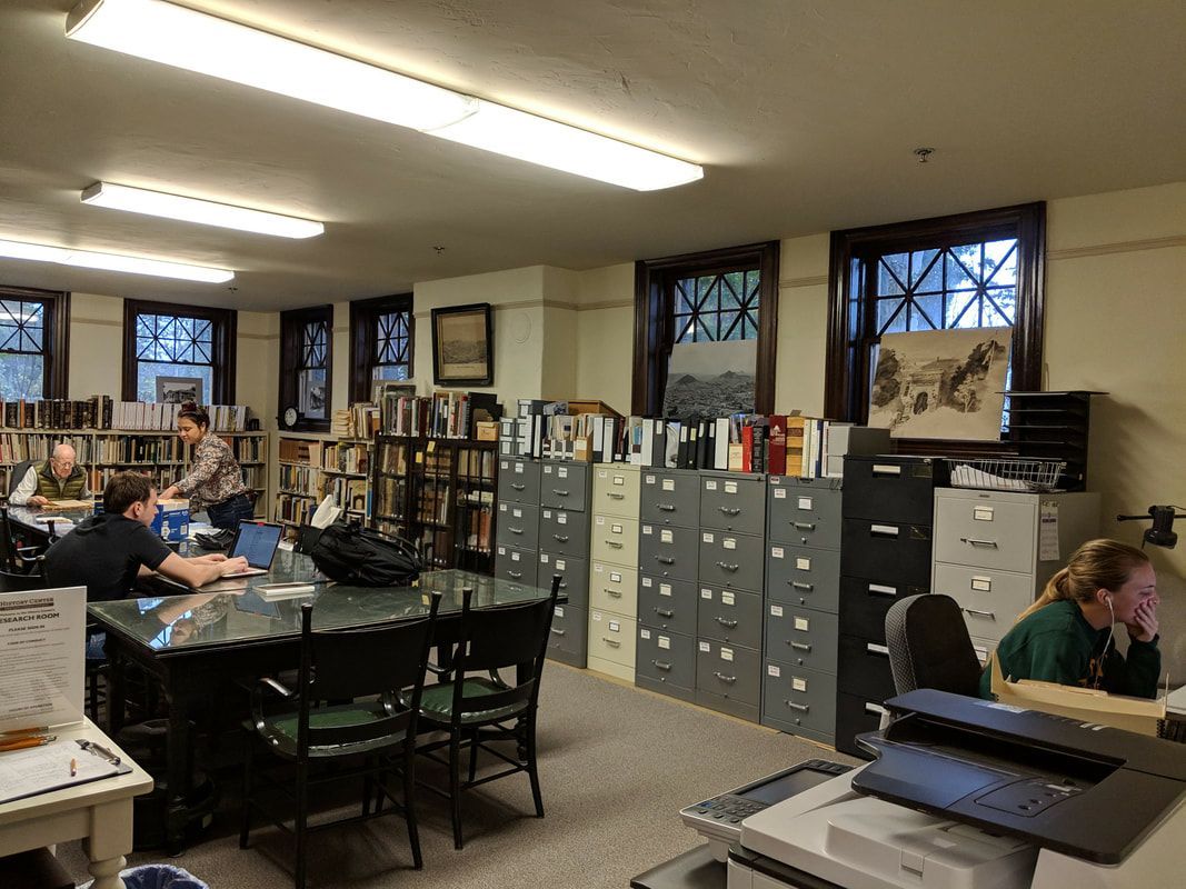 A group of people are sitting at tables in a library.