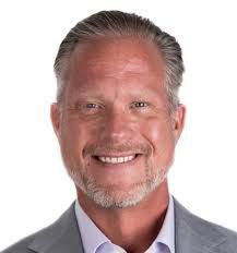 A man with a beard and a suit is smiling for the camera.