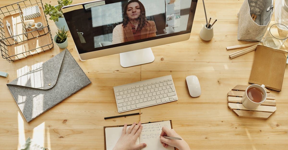 A person is sitting at a desk with a computer and a notebook.
