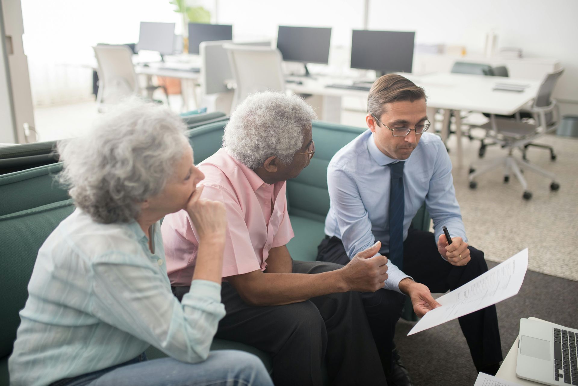 A group of people are sitting on a couch looking at a piece of paper.
