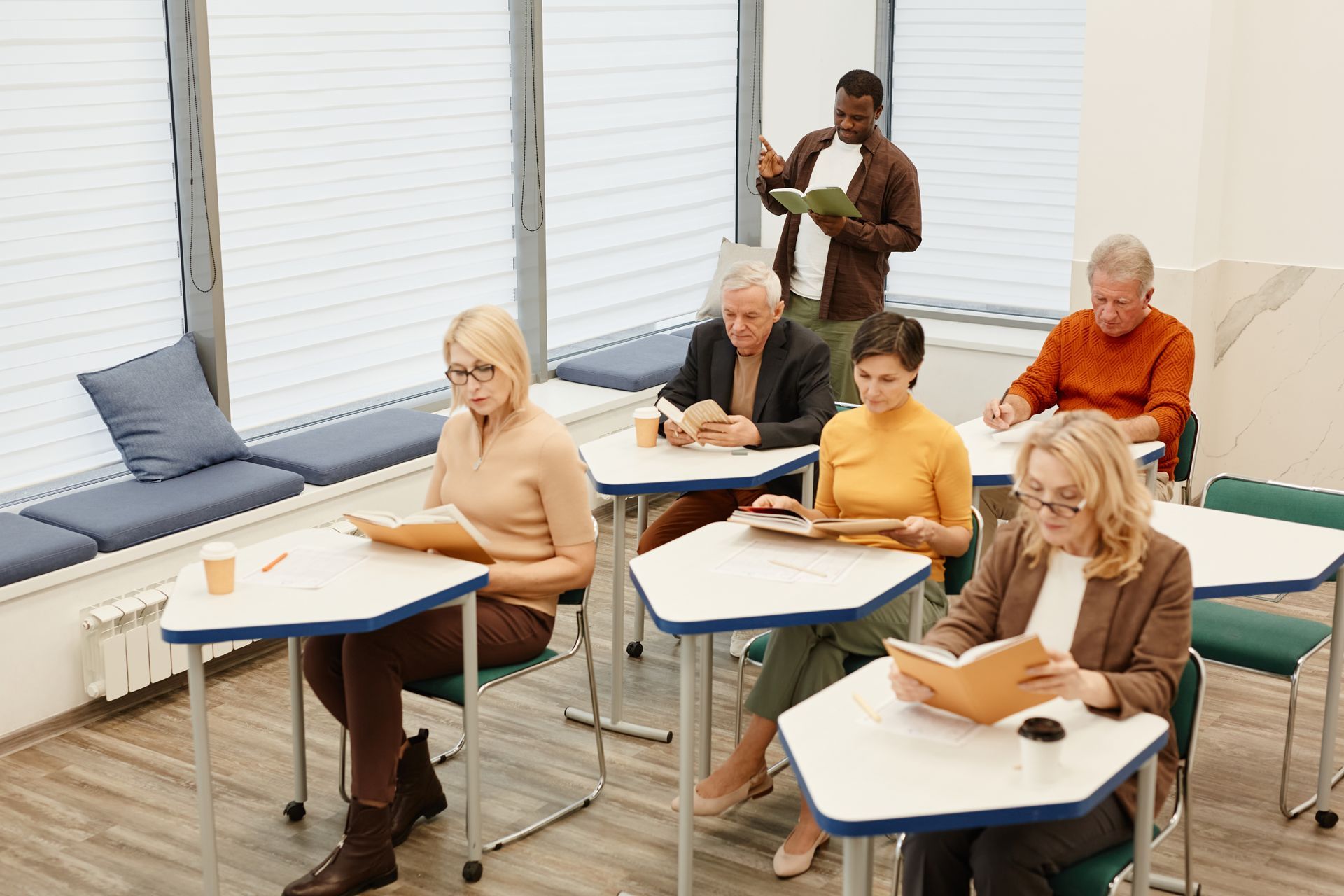 A group of people are sitting at tables in a classroom.