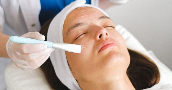 A woman is getting a facial treatment with a brush.