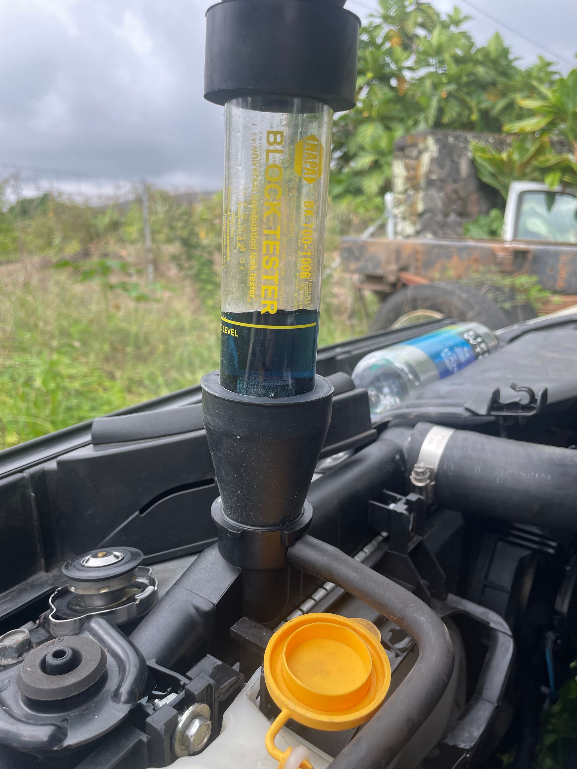 A close up of a car engine with a bottle of water in the background.